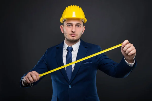 Männlicher Bauarbeiter mit Helm, der einen Meter hält — Stockfoto