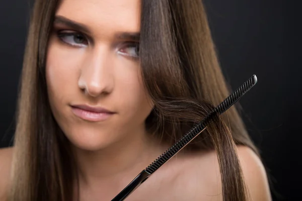Jovem mulher no fundo escuro pentear o cabelo — Fotografia de Stock