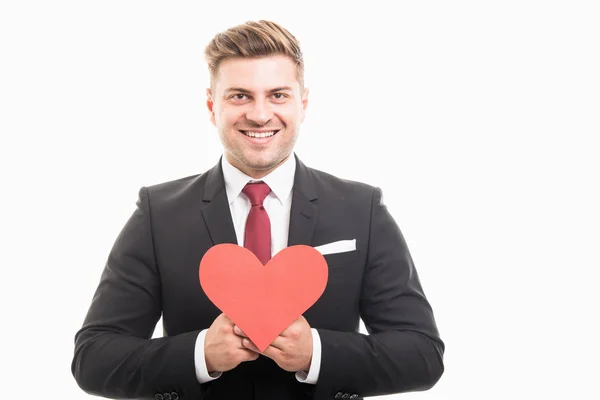 Handsome manager holding red heart shape and smiling — Stock Photo, Image