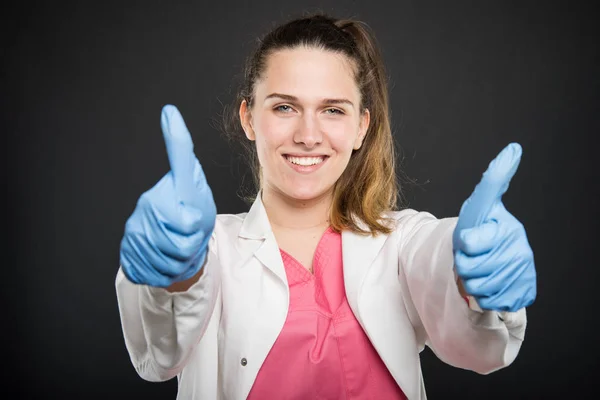 Junge Ärztin Portrait trägt Robe zeigt doppelt wie — Stockfoto