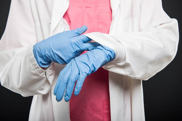 Крупный план доктора, устанавливающего ее стерильные перчатки
