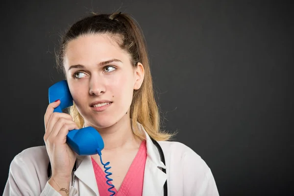 Портрет молодого доктора, разговаривающего у синего телефонного приемника — стоковое фото