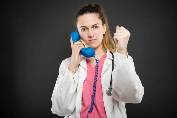 Doctora hablando en el receptor de teléfono azul mostrando puño — Foto de Stock