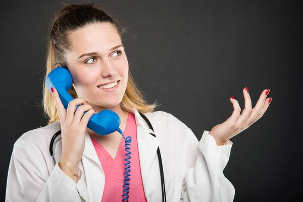 Женщина-врач разговаривает в синем телефонном приемнике и жестикулирует — стоковое фото