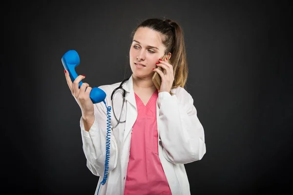 Lekarka mówi o smartphone patrząc na telefon odbieranie — Zdjęcie stockowe