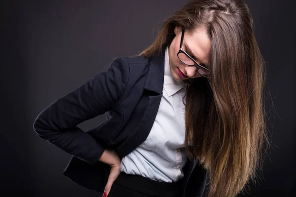 Giovane donna d'affari che tiene la parte bassa della schiena nel dolore — Foto Stock