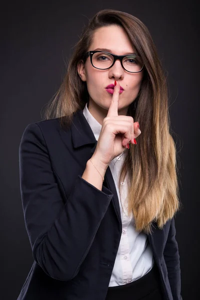 Schöne weibliche Managerin mit dem Finger auf den Lippen — Stockfoto