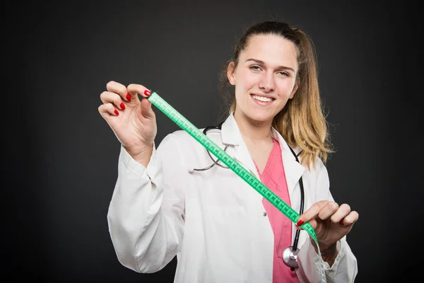 Attraente medico femminile che tiene il nastro di misurazione — Foto Stock