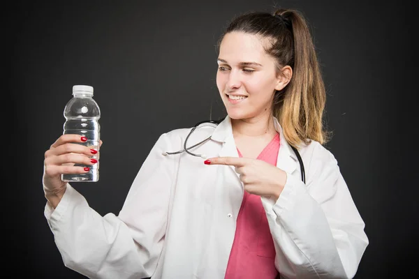 Nutricionista femenina señalando botella de agua y sonriendo — Foto de Stock