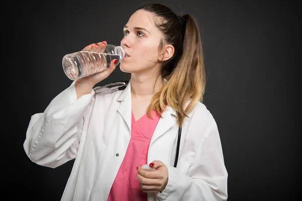 Doctora joven bebiendo de la botella de agua — Foto de Stock