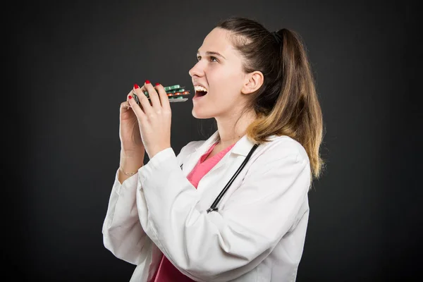 Atractiva doctora comiendo manojo de ampollas con tabletas — Foto de Stock