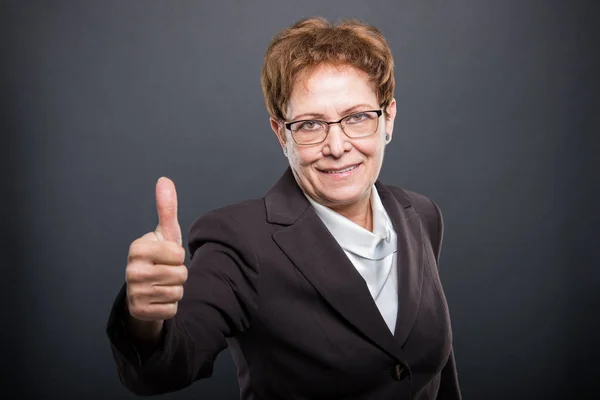 Старшая деловая леди показывает, как жест — стоковое фото