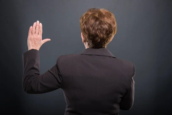Visão traseira dos negócios seniores senhora fazendo juramento — Fotografia de Stock