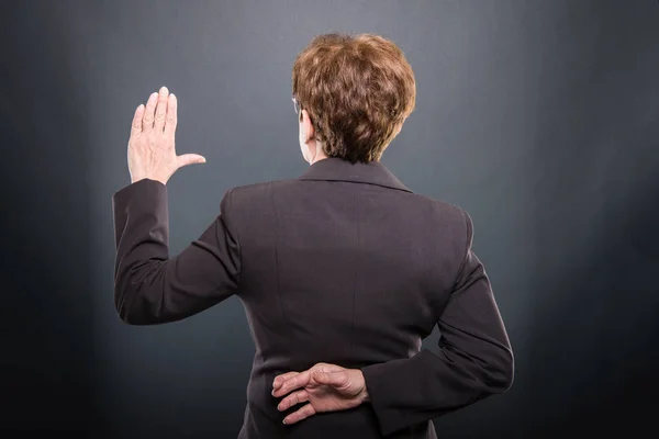 Rückansicht einer Seniorin, die einen falschen Eid ablegt — Stockfoto