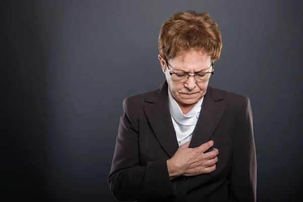 Business senior lady holding chest like heart ache