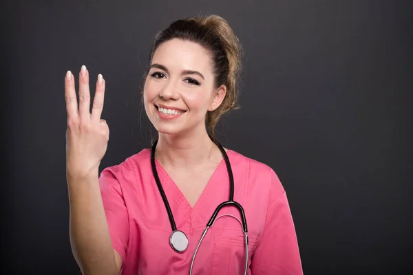Πορτρέτο του ελκυστική γυναίκα γιατρός δείχνει αριθμό τρία χειρονομία — Φωτογραφία Αρχείου