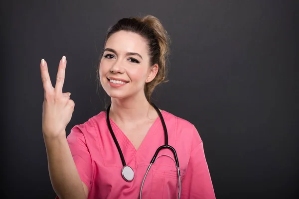 Portret atrakcyjna pani doktor pokazuje gest numer dwa — Zdjęcie stockowe
