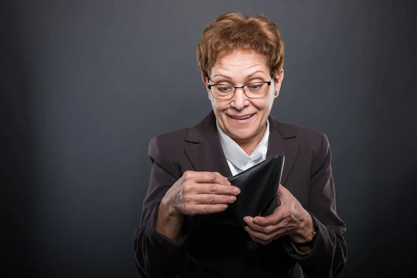 Старшая деловая леди, которая смотрит в бумажник — стоковое фото