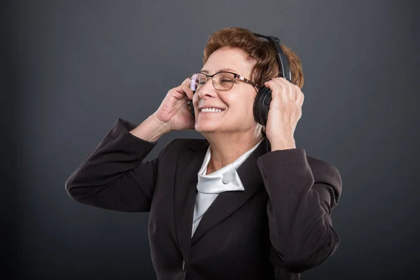 Portrait of business senior lady enjoying listening to headphone — Stock Photo, Image