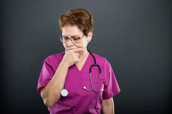 Portrait of senior lady doctor making thinking gesture
