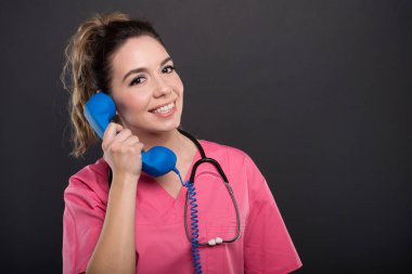 Portrait of beautiful young doctor talking at telephone receiver clipart
