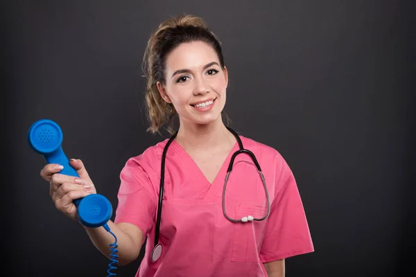 Portrait of beautiful young doctor holding telephone receiver — Stock Photo, Image