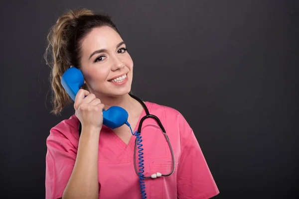 Portrait of beautiful young doctor talking at telephone receiver — Stock Photo, Image