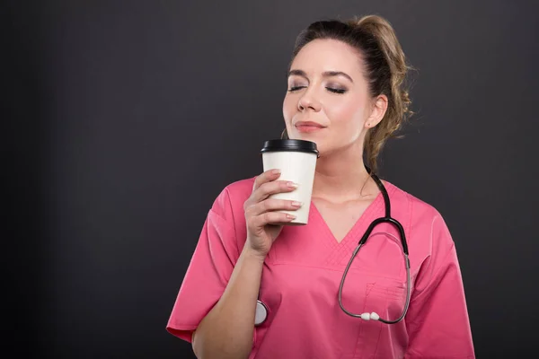 Retrato de un hermoso médico joven oliendo café para llevar — Foto de Stock