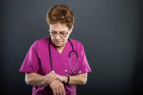 Portrait of senior lady doctor holding wrist like hurting