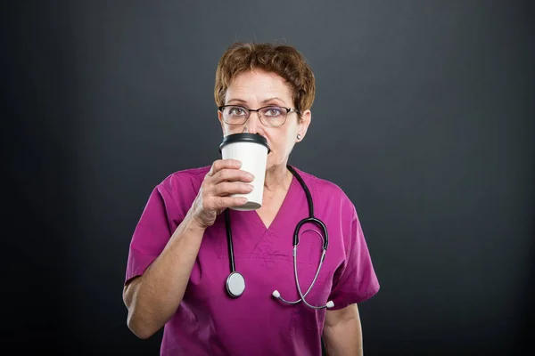 Retrato de la doctora mayor bebiendo café para llevar — Foto de Stock