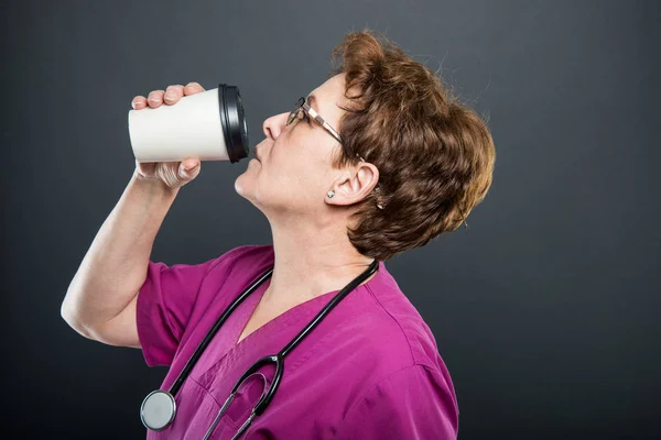 Boční pohled na starší paní doktorka pití kávy s sebou — Stock fotografie