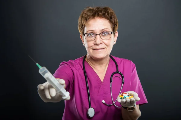 Enfoque selectivo de la doctora senior sosteniendo jeringa y pastillas — Foto de Stock