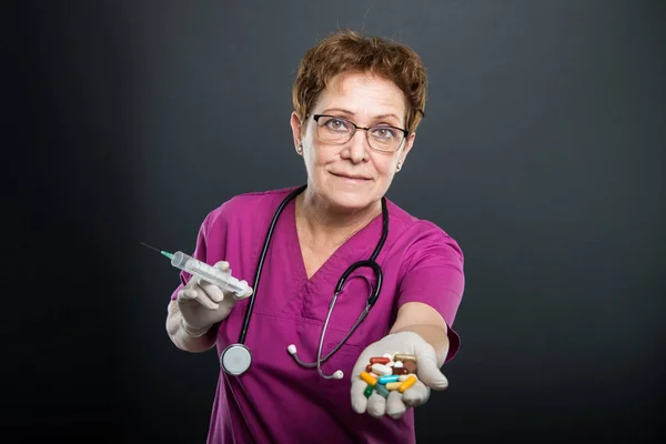 Portrait of senior lady doctor offering bunch of pills