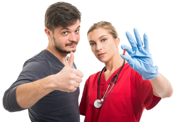 Мужской пациент показывает, как и женщина врач держит Pil — стоковое фото