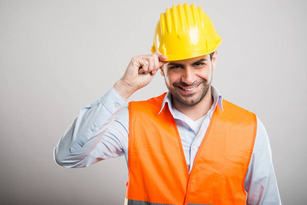 Портрет молодого архитектора, держащего шлем как салют
