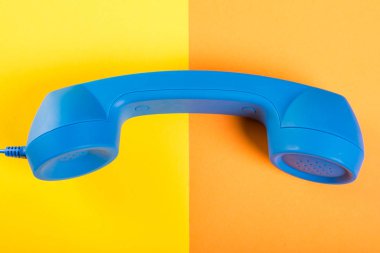 Bir büyük mavi telefon ahizesi sarı ve turuncu adam üzerinde