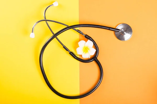 One stethoscope and flower on yellow and orange backgroun — Stock Photo, Image