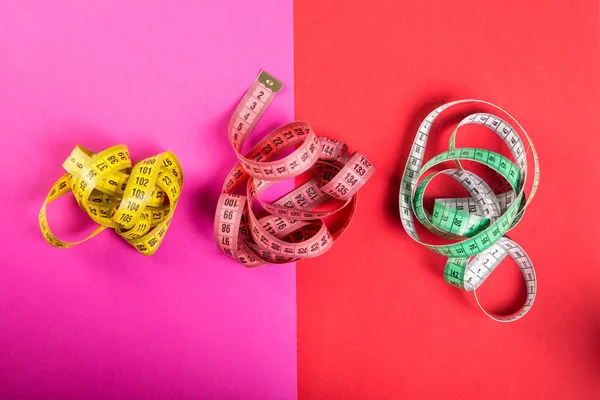 Três fita métrica em fundo vermelho e rosa — Fotografia de Stock