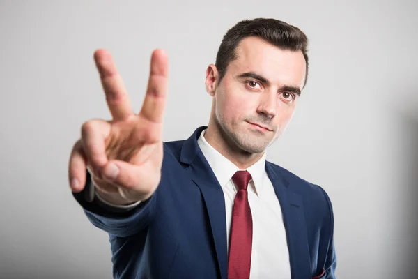 Portrait of young attractive business man showing peace gesture — Stock Photo, Image