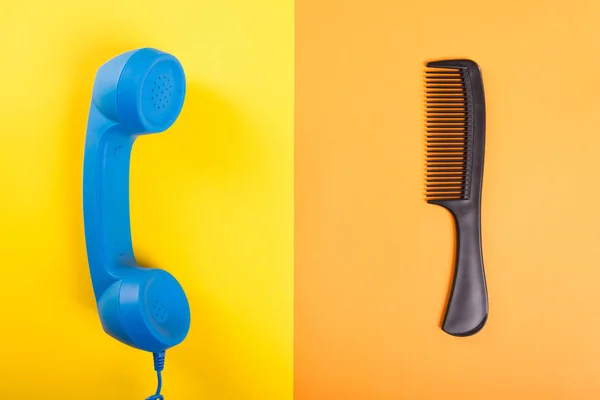 Um pente e receptor de telefone azul em amarelo e laranja backgr — Fotografia de Stock