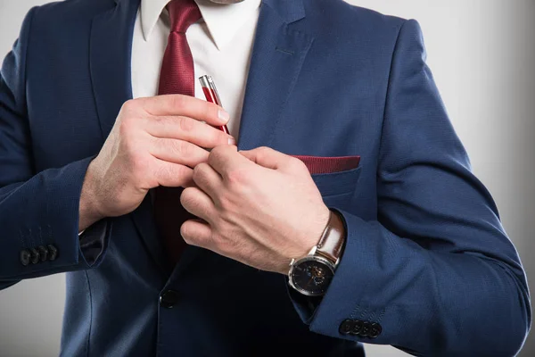 Крупный план бизнесмена в костюме, кладущего ручку в карман — стоковое фото