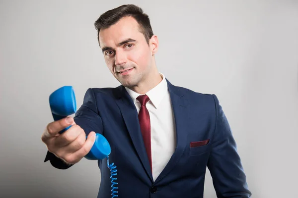 Homem de negócios atraente entregando receptor de telefone azul — Fotografia de Stock