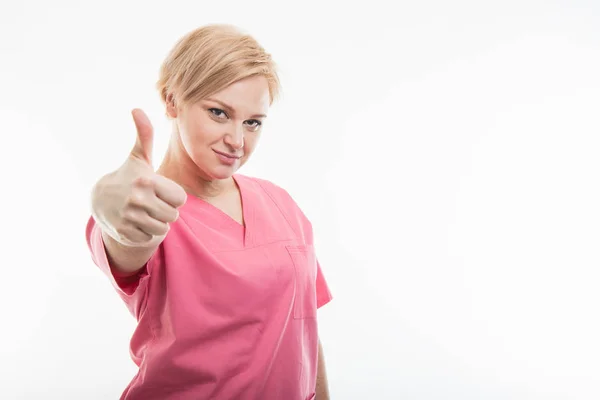 漂亮的女护士穿着粉红色的磨砂显示像手势 — 图库照片