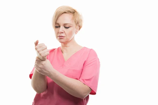 Attractive female nurse wearing pink scrubs holding wrist like h — Stock Photo, Image
