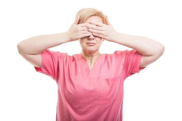 Enfermeira feminina vestindo esfoliação rosa cobrindo os olhos como cegos — Fotografia de Stock