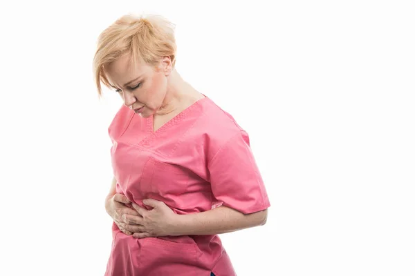 Atractiva enfermera vestida con matorrales rosados sosteniendo el estómago como —  Fotos de Stock