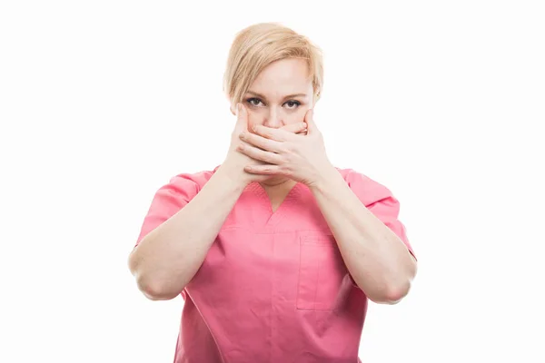 Enfermeira feminina vestindo esfoliação rosa cobrindo a boca como mudo concep — Fotografia de Stock