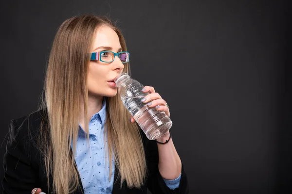 水のボトルから飲む青メガネを身に着けている女性のビジネス — ストック写真
