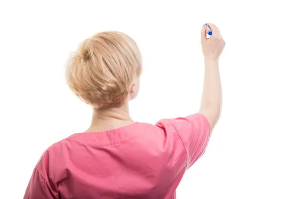 Achteraanzicht van vrouwelijke verpleegkundige draagt roze scrubs schrijven met blauw — Stockfoto