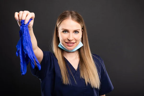 Hermosa dentista femenina usando mascarilla que sostiene el guante —  Fotos de Stock